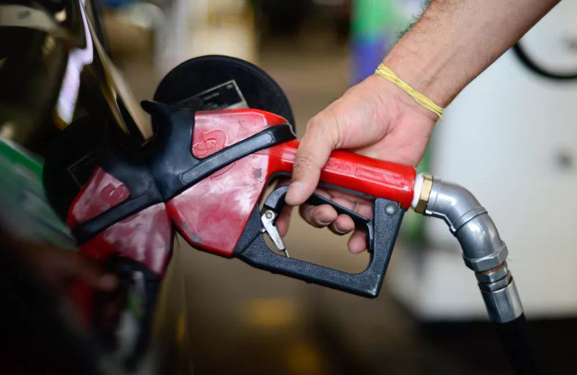 Foto de uma pessoa enchendo o tanque do carro com uma mangueira de combustível