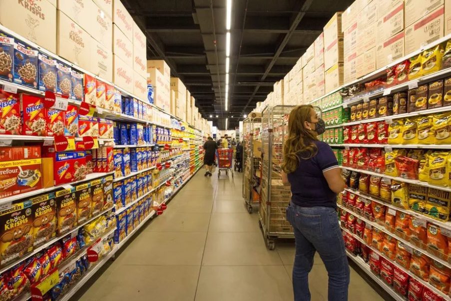 Foto de uma ala de supermercado com gôndolas e clientes