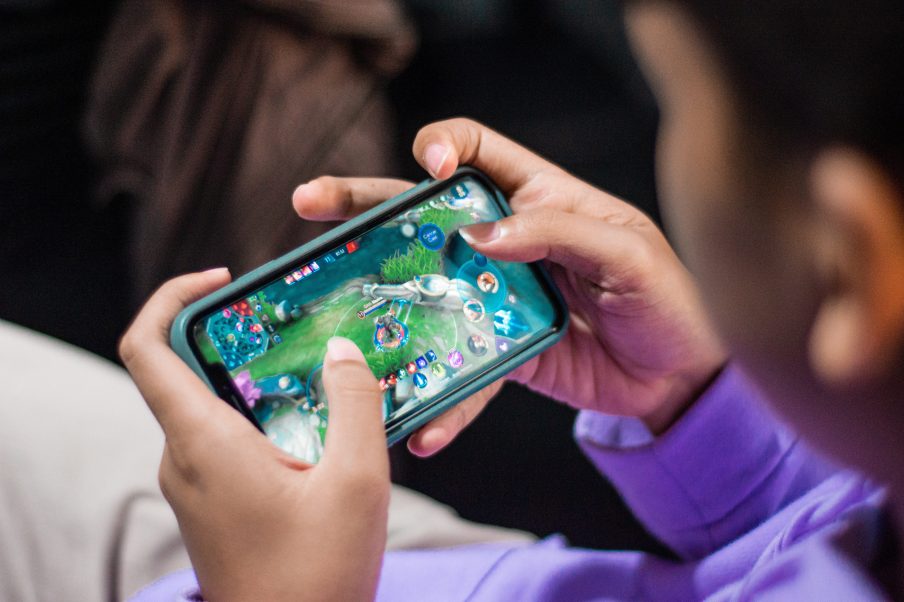 Jovem joga game eletrônico no seu celular.