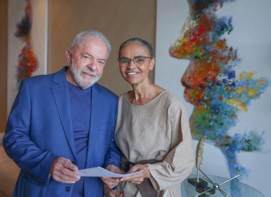 Foto de Marina Silva à esquerda e Luiz Inácio Lula da Silva à direita. Ele usa um palitó azul e ela usa um vestido cinza