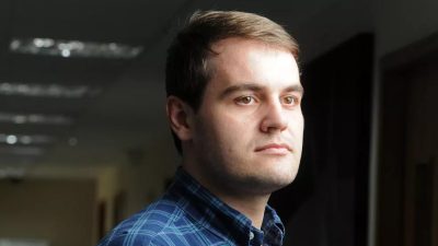Homem branco olha para frente em pose de 3/4