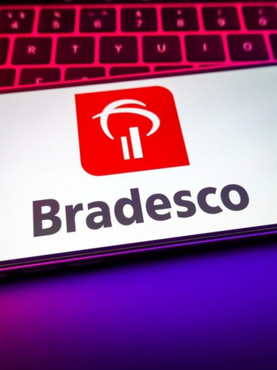 Foto do logo do Bradesco (BBDC4) em tela de celular com fundo branco. A matéria comenta sobre recomendações das ações de Bradesco e Santander (SANB11)