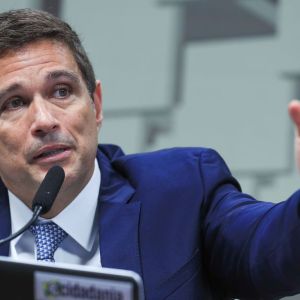 Foto do presidente do Banco Central, Roberto Campos Neto. Ele fala a um microfone e gesticula com o braço esquerdo.
