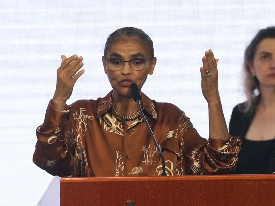 Foto de Marina Silva erguendo os braços durante cerimônia de posse como ministra