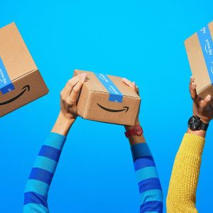 A imagem mostra duas caixas com escrito "Prime Day" seguradas por mãos.