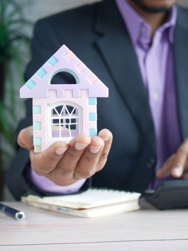 Foto para a matéria sobre quanto rendem R$ 5 mil em fundos imobiliários em que aparece um homem segurando uma maquete de uma casa e com a outra mão fazendo cálculos em uma calculadora.