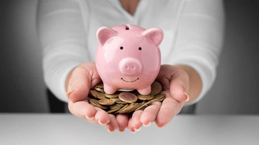 Mãos seguram moedas com um porquinho simbolizando investimento na poupança