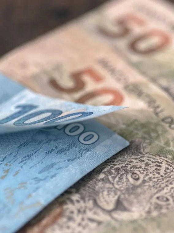 Foto de uma nota de 100 reais e duas de 50 reais. A matéria fala sobre o desempenho de fundos multimercado em 2023