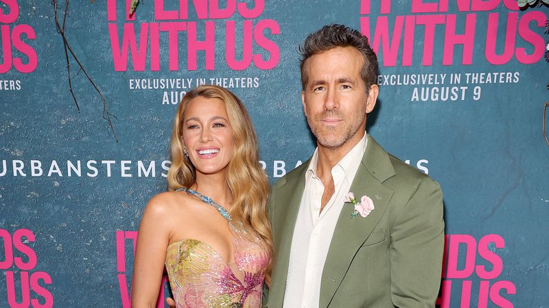 Foto de um casal. A mulher é loira e veste um vestido colorido, enquanto o homem está de terno.