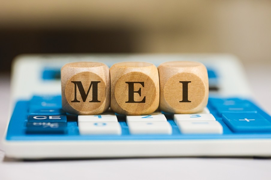 MEI, MICROEMPREENDEDOR INDIVIDUAL The acronym MEI for Individual Microentrepreneur in Brazilian Portuguese written on wooden dice lying on top of a calculator.