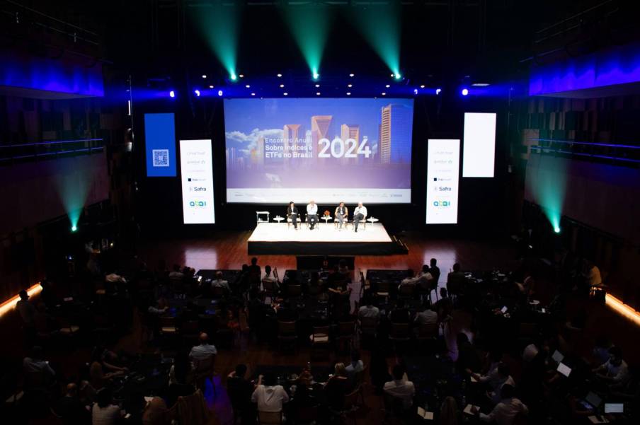 Foto do evento ETF Masterclass, com pessoas sentadas ao na plateia e quatro painelistas no palco