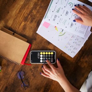 Imagem de uma pessoa com papéis e calculadora para ilustrar reportagem sobre diversificar investimentos