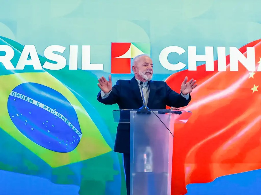 Foto do presidente do Brasil, Luiz Inácio Lula da Silva, em pódio durante visita à China, onde anunciou investimentos de empresas como GWM, Keeta e Mixue no Brasil